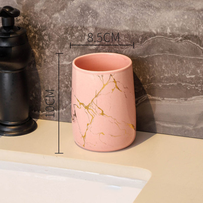 Pink ceramic bathroom tumbler with gold marble pattern measuring 10 centimeters tall and 8.5 centimeters wide