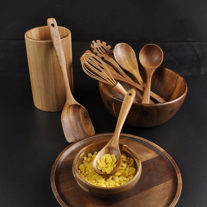 Wooden kitchen utensils arranged near a breakfast bowl on a dark table