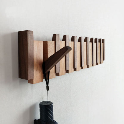Solid wood black walnut wall-mounted coat rake with an umbrella hanging on it.