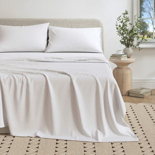 Neatly made bed with white bedding in a bedroom setting.
