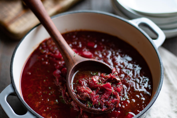 wood soup ladle in dutch oven with red sauce