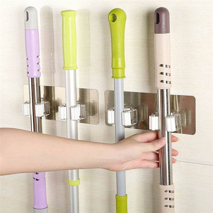Wall-mounted mop and broom holders securing four household cleaning tools.