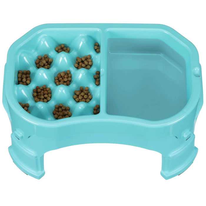 Neater Slow Feeder Double Diner raised in Aqua with kibble and water inside the feeder against a white background.