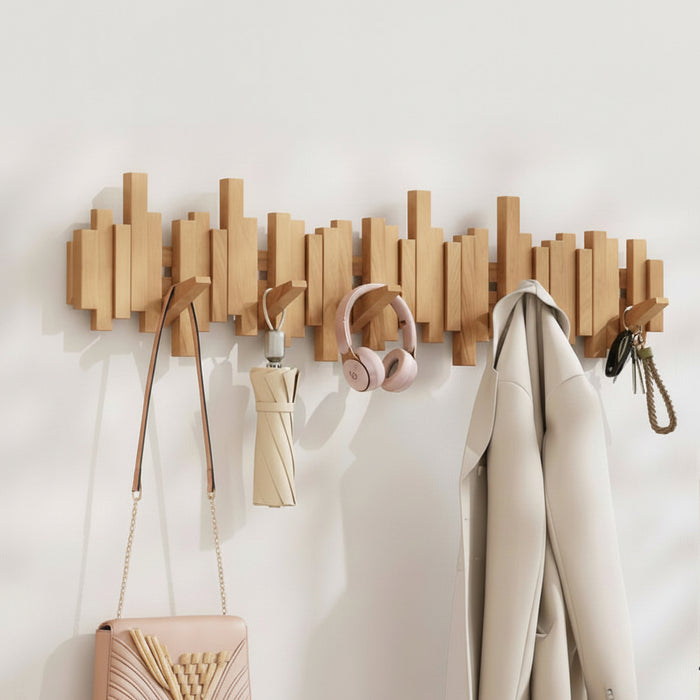 Wooden wall mounted coat rack with hooks holding bags, headphones, clothing, and accessories in an entryway