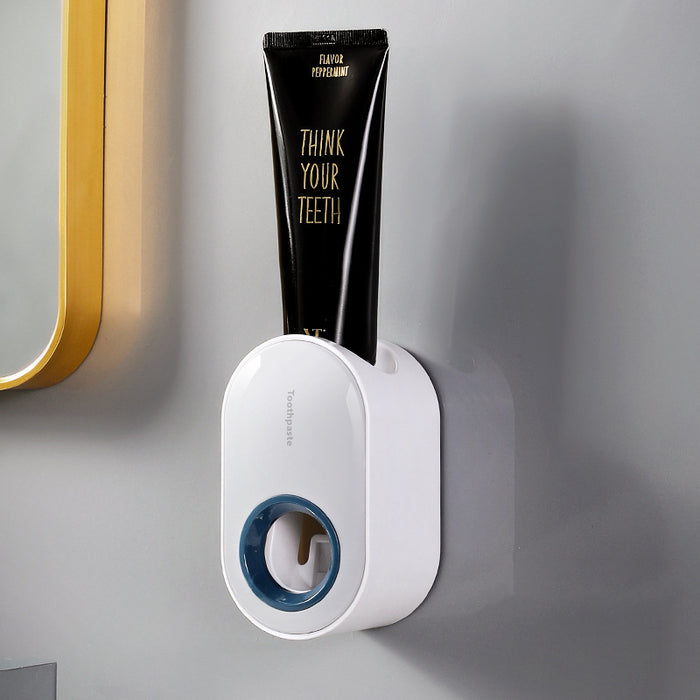 White wall-mounted toothpaste dispenser with an ocean-blue accent and a black toothpaste tube.