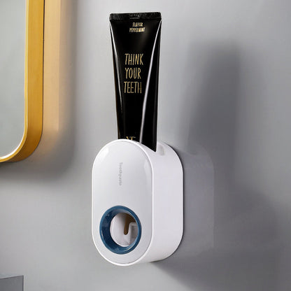 White wall-mounted toothpaste dispenser with an ocean-blue accent and a black toothpaste tube.