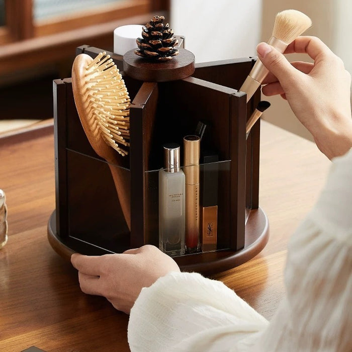 Rotating wooden makeup organizer holding cosmetics, makeup brushes, perfume, and a hairbrush on a vanity