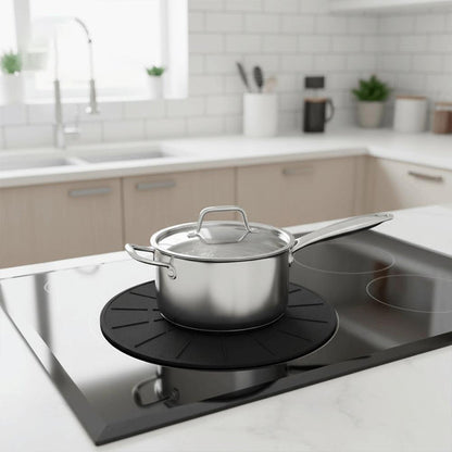 Silver pot sitting on top on cooktop mat on an induction stovetop.