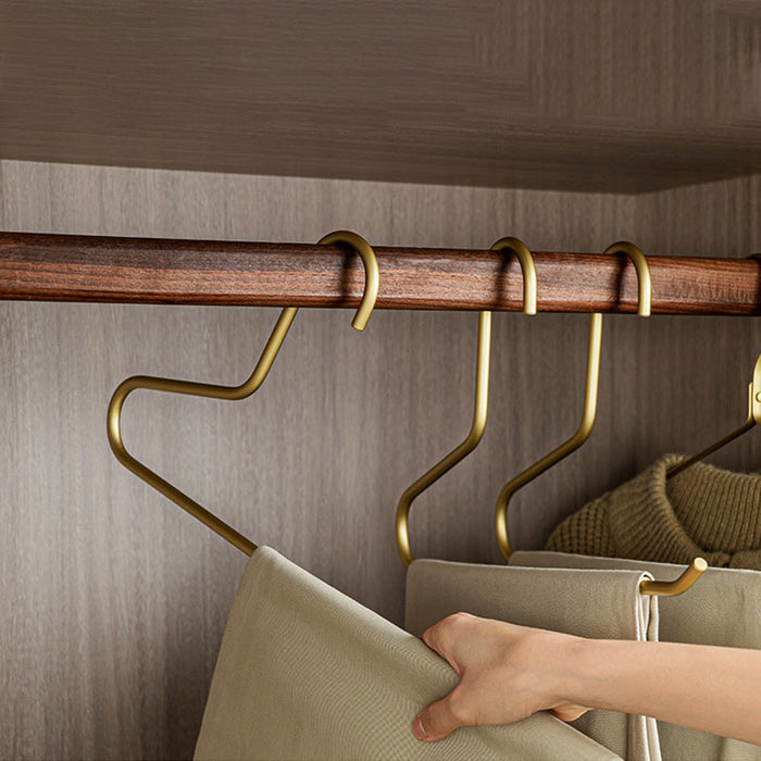 Person sliding folded pants onto a gold open-ended space-saving closet hanger