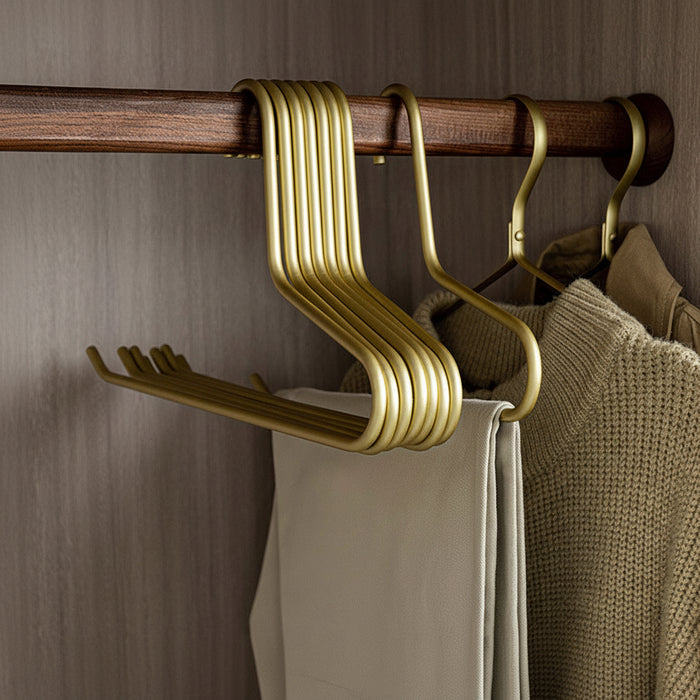 Champagne gold aluminum space-saving pants rack holding folded trousers in a closet