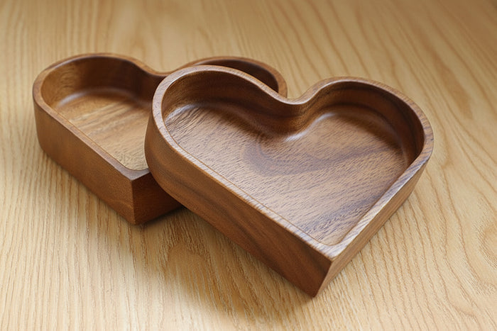 Heart-shaped wooden serving tray with divided compartments filled with nuts and snacks