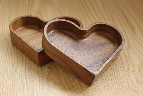 Heart-shaped wooden serving tray with divided compartments filled with nuts and snacks