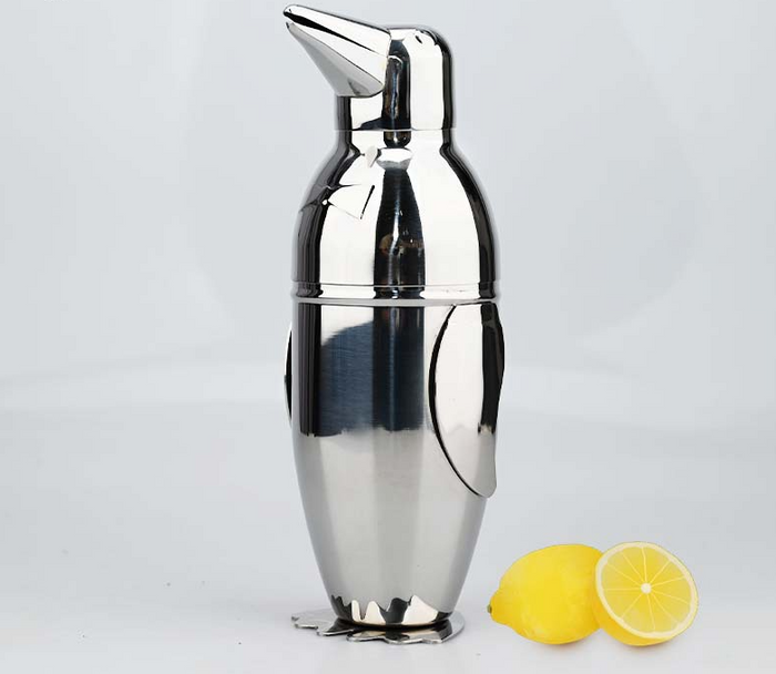 Stainless steel penguin cocktail shaker beside lemon halves