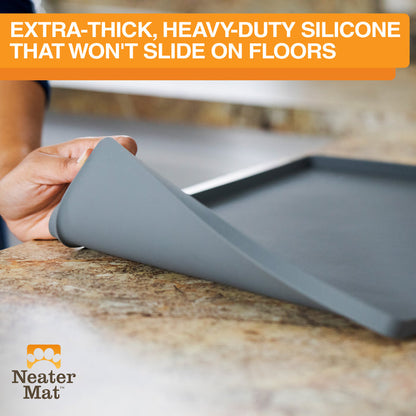 Gray Neater Mat being rolled out on a countertop with text above that says how the silicone bottom won't slide on floors.